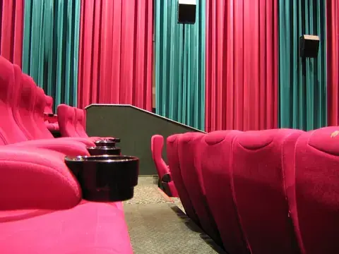 Rows of red cinema seats in front of a curtain
