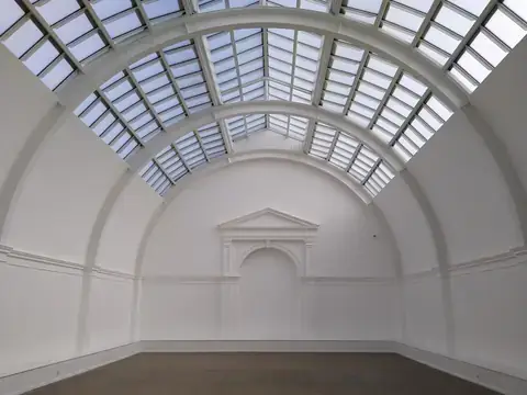 An empty white exhibition hall under a glass roof