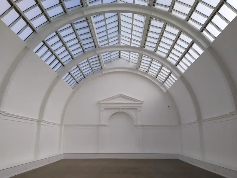An empty white exhibition hall under a glass roof