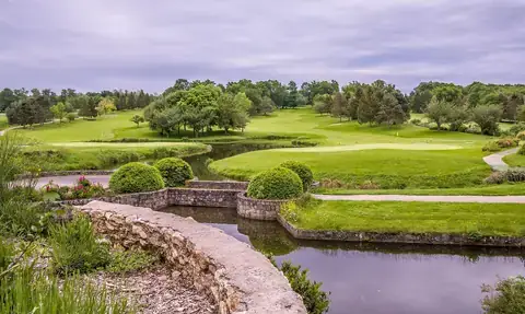 A green golf course with a stone bridge over water