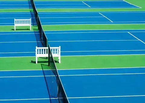 Blue hard tennis courts with umpire benches