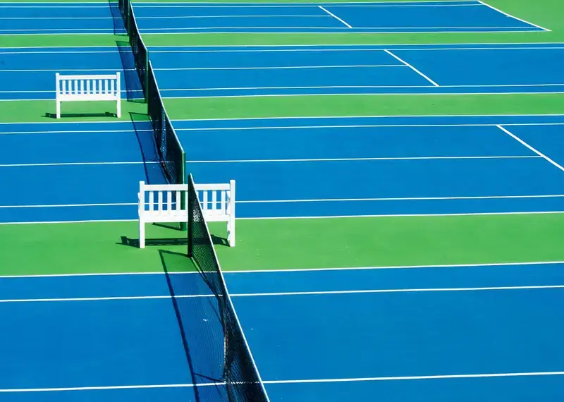 Blue hard tennis courts with umpire benches