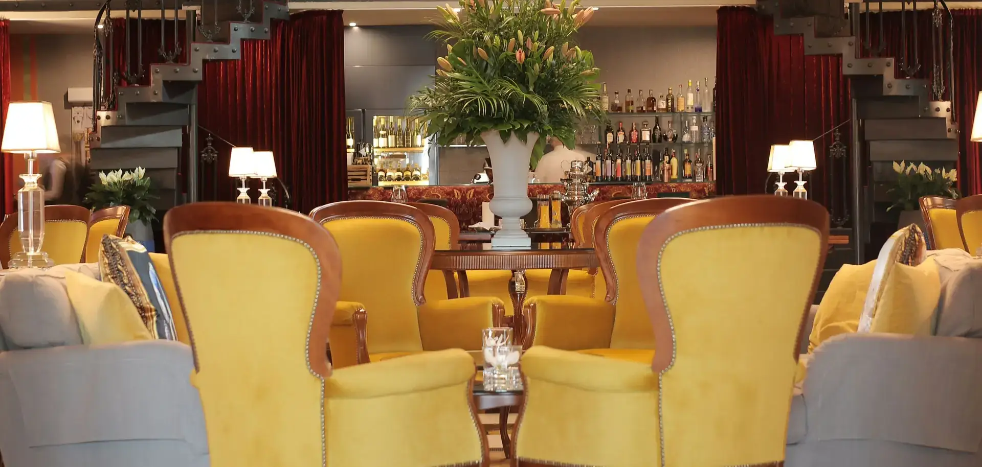 A hotel lounge with velvet armchairs beneath a chandelier