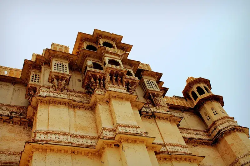 Carved sandstone balconies of the City Palace, Udaipur, seen from below against a pale sky