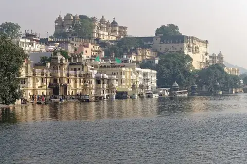 The City Palace, Udaipur, rising above old lakeside houses and ghats on Lake Pichola in soft morning light