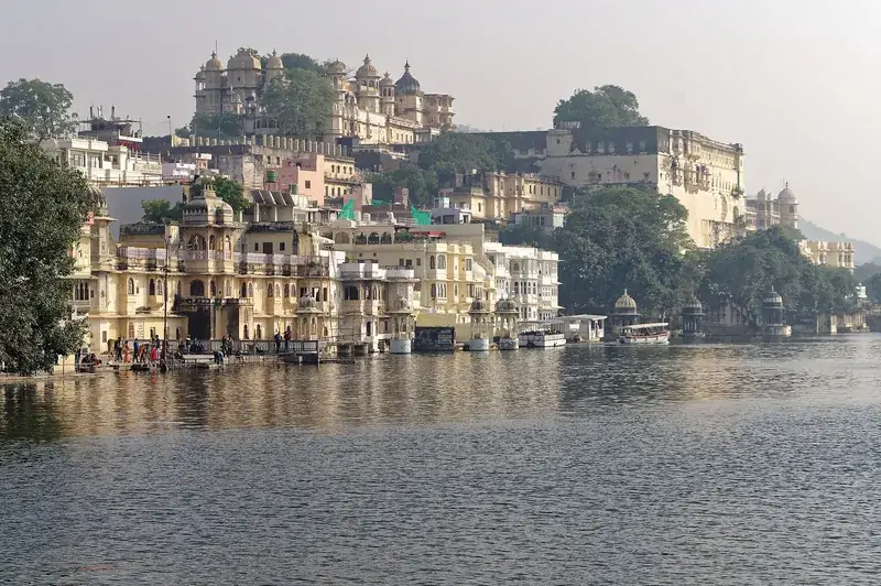 The City Palace, Udaipur, rising above old lakeside houses and ghats on Lake Pichola in soft morning light