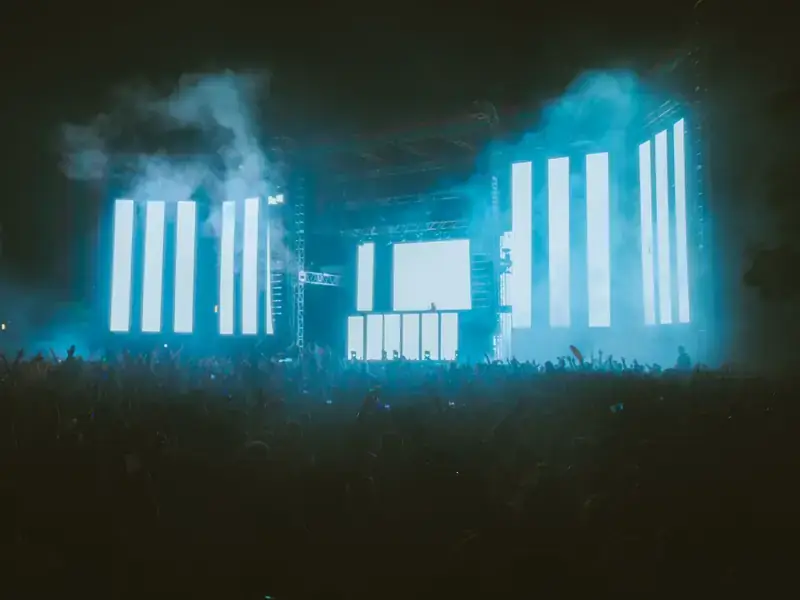 A festival stage glowing through haze above a night crowd